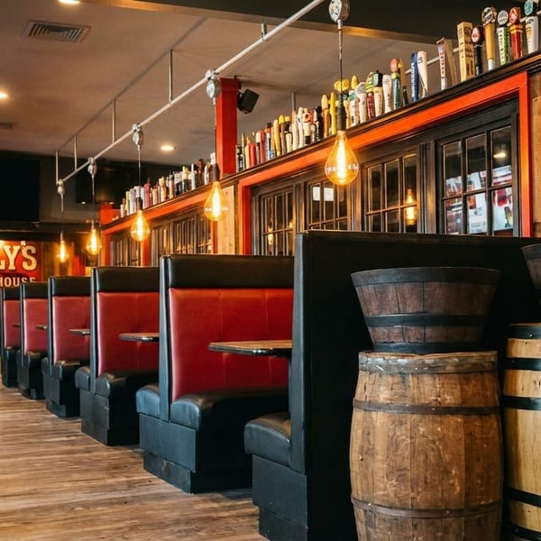 Interior of Scally's Irish Ale House with red booths, wooden barrels, and a bar.