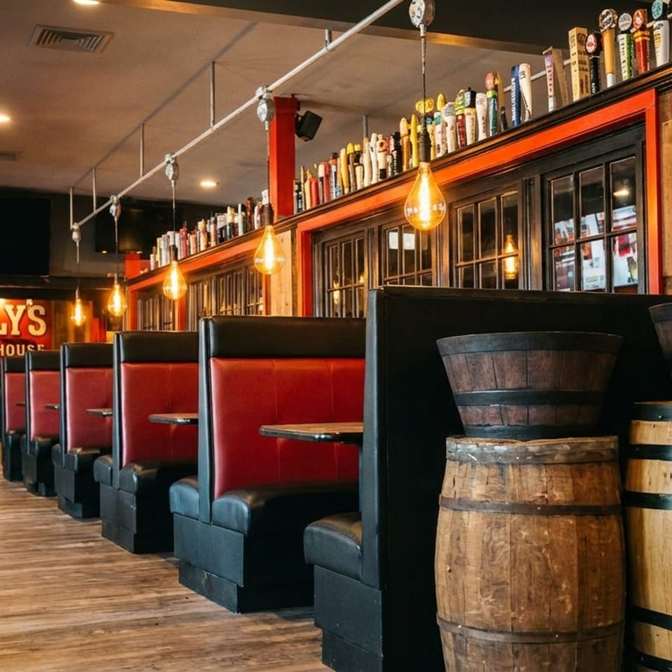 Interior of Scally's Irish Ale House with red booths, wooden barrels, and a bar.