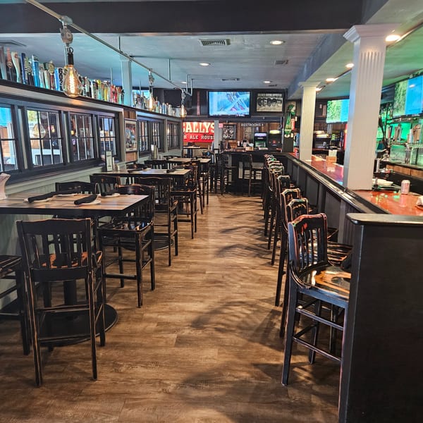 Interior of Bally's Ale House, showing empty tables, chairs, and a long bar with beer taps.