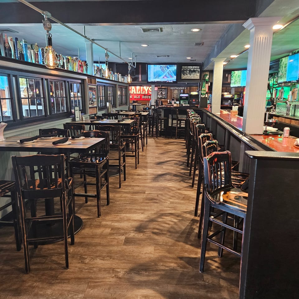 Interior of Bally's Ale House, showing empty tables, chairs, and a long bar with beer taps.