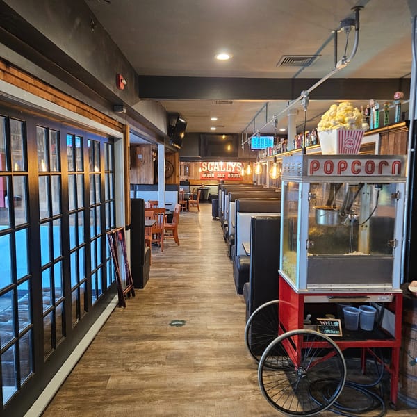 Interior of Scally's Irish Ale House with a popcorn machine, booths, and a sign for the bar.