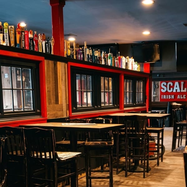 Interior of Scally's Irish Ale House, featuring tables, chairs, and a bar with many beer taps.