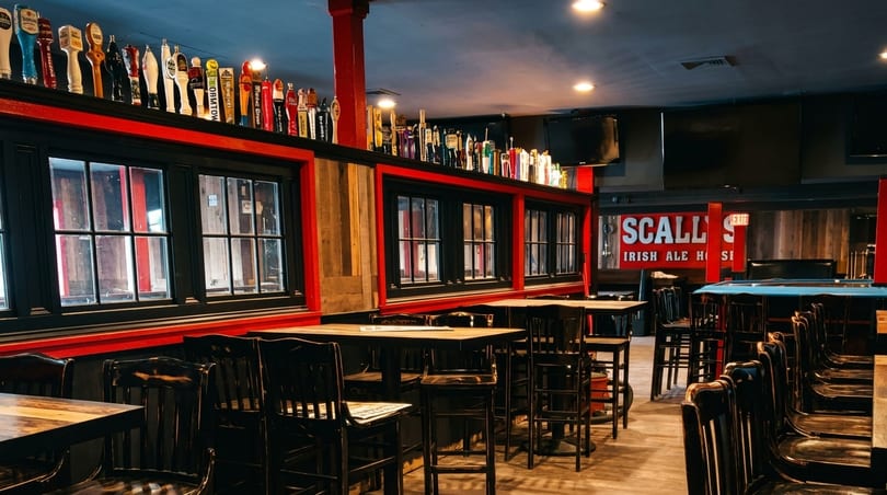 Interior of Scally's Irish Ale House, featuring tables, chairs, and a bar with many beer taps.