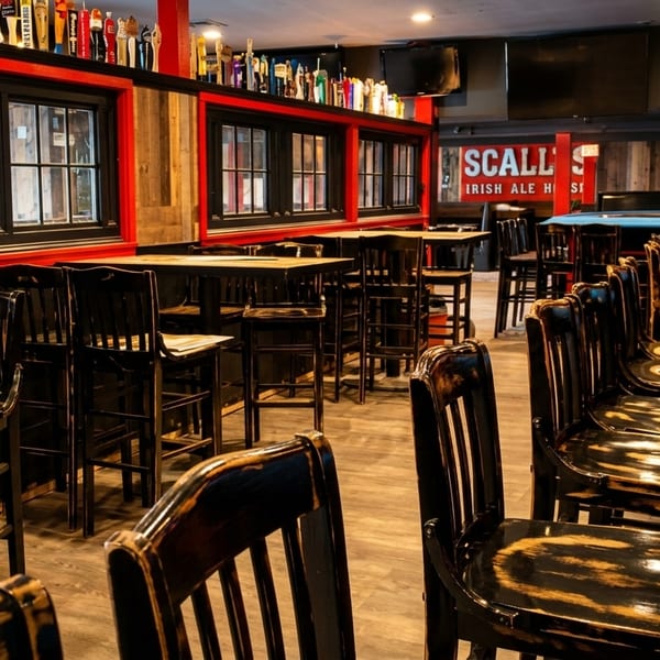 Interior of a pub with high-top tables, bar stools, and a long wooden bar.